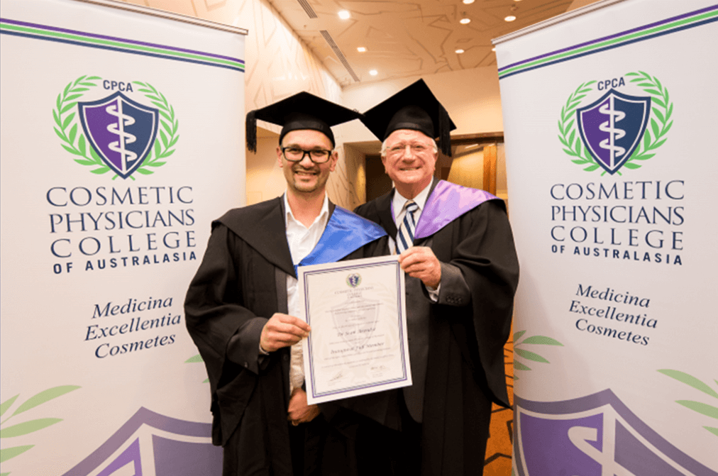 Doug & Sean Arendse Two graduates holding a "cosmeceuticals certification" in front of Cosmetic Physicians College banners